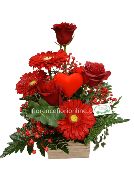 3 rose rosse, gerbere rosse e verde decorativo in vasetto di legno.